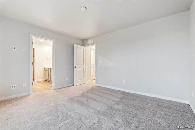 19019 E 94th Pl, Commerce City, CO 80022 - unfurnished bedroom featuring light carpet, baseboards, and connected bathroom