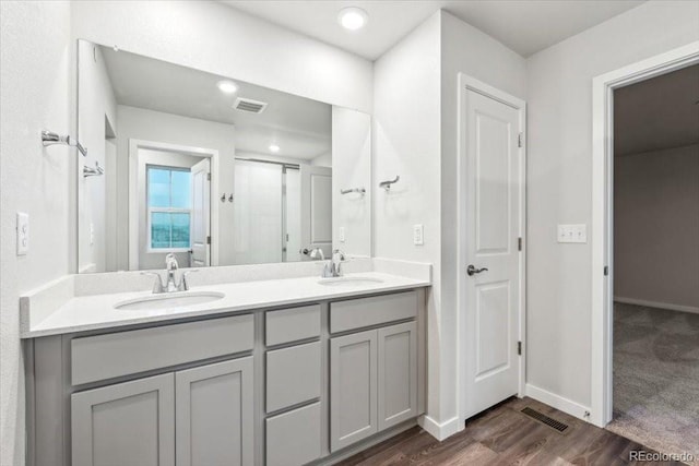 19019 E 94th Pl, Commerce City, CO 80022 - bathroom featuring double vanity, wood finished floors, a shower with shower door, and baseboards