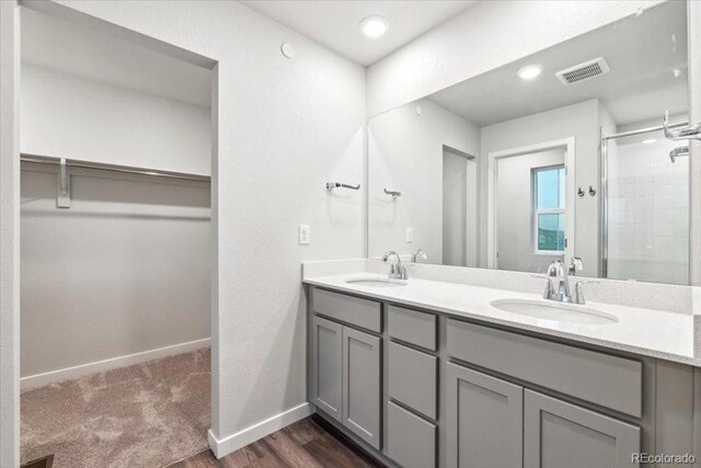 19019 E 94th Pl, Commerce City, CO 80022 - full bathroom featuring a spacious closet, double vanity, a shower stall, baseboards, and wood finished floors