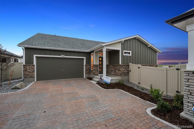 5142 N Quemoy Ct, Aurora, CO 80019 - view of front facade featuring board and batten siding, a shingled roof, an attached garage, and stone siding