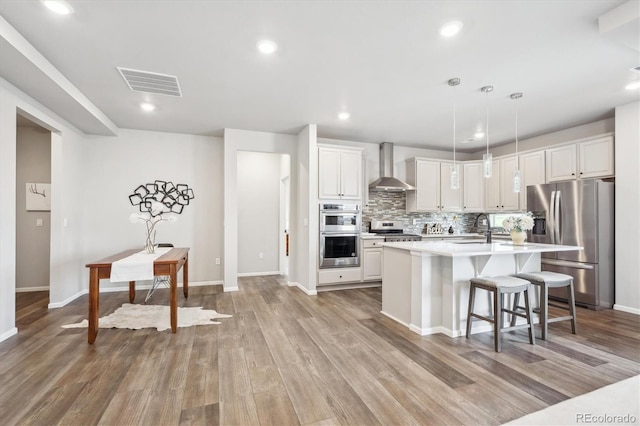 5142 N Quemoy Ct, Aurora, CO 80019 - kitchen featuring stainless steel appliances, wall chimney range hood, a sink, light countertops, and backsplash