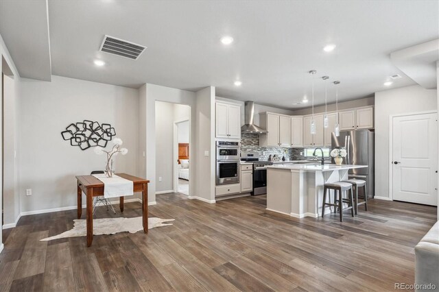 5142 N Quemoy Ct, Aurora, CO 80019 - kitchen with appliances with stainless steel finishes, wall chimney exhaust hood, light countertops, backsplash, and a sink