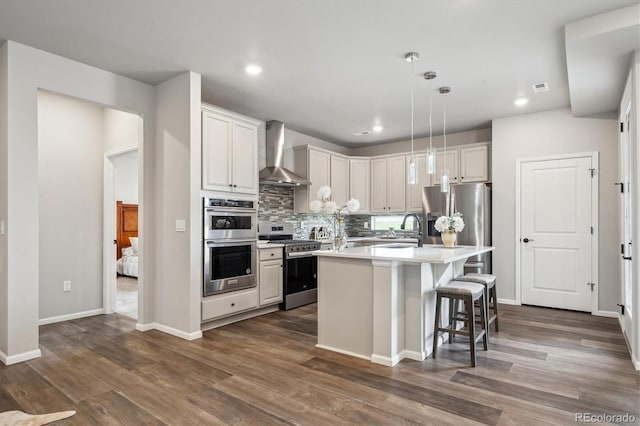 5142 N Quemoy Ct, Aurora, CO 80019 - kitchen with stainless steel appliances, wall chimney exhaust hood, light countertops, decorative backsplash, and a center island with sink