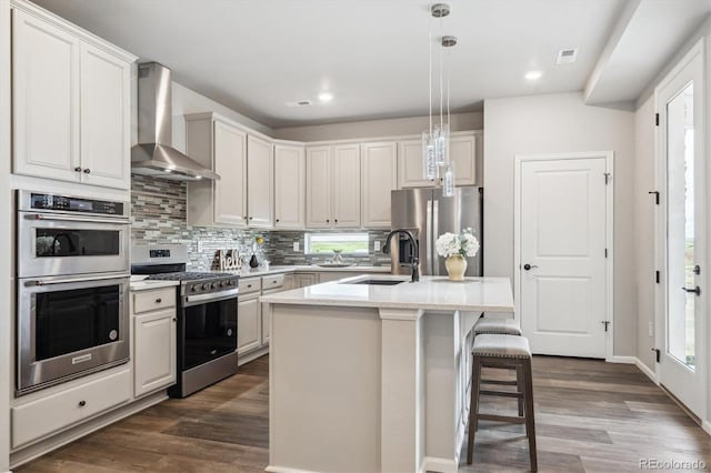 5142 N Quemoy Ct, Aurora, CO 80019 - kitchen featuring wall chimney range hood, a sink, appliances with stainless steel finishes, dark wood-type flooring, and recessed lighting