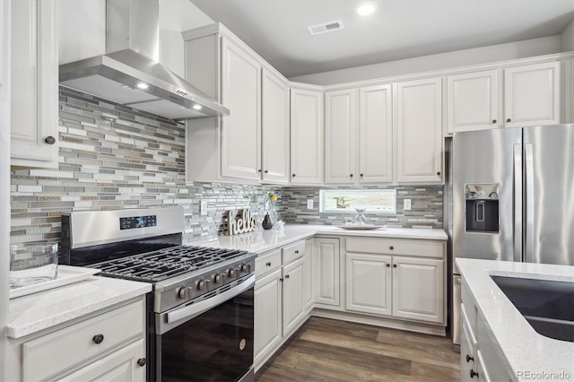 5142 N Quemoy Ct, Aurora, CO 80019 - kitchen with appliances with stainless steel finishes, wall chimney exhaust hood, white cabinets, light stone countertops, and recessed lighting