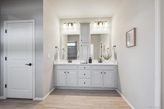 5142 N Quemoy Ct, Aurora, CO 80019 - bathroom featuring double vanity, wood finished floors, and baseboards