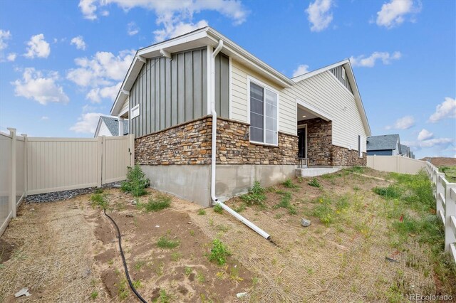 5142 N Quemoy Ct, Aurora, CO 80019 - view of side of home with board and batten siding, stone siding, and a fenced backyard