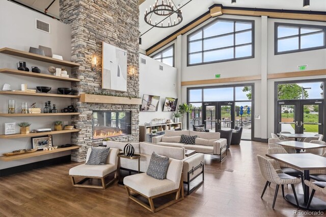 5142 N Quemoy Ct, Aurora, CO 80019 - living room with french doors, wood finished floors, high vaulted ceiling, a chandelier, and a fireplace