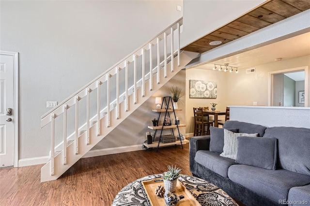 living area featuring dark wood-type flooring, visible vents, baseboards, and stairs