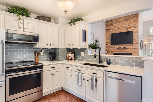 kitchen featuring light countertops, backsplash, appliances with stainless steel finishes, white cabinets, and a sink