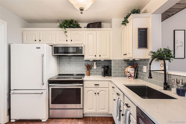 kitchen featuring dark wood finished floors, a sink, light stone countertops, stainless steel appliances, and backsplash