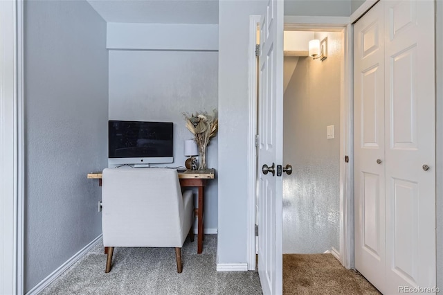 carpeted office space featuring baseboards and a textured wall