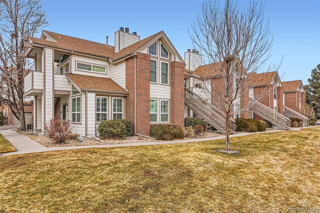 view of property exterior with stairs, a chimney, a lawn, and brick siding