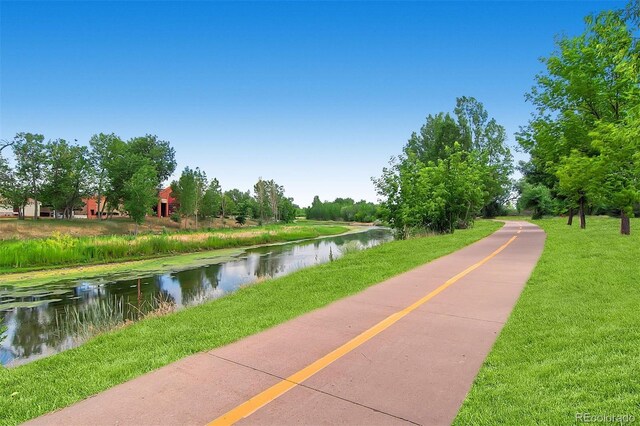 surrounding community with a water view and a lawn