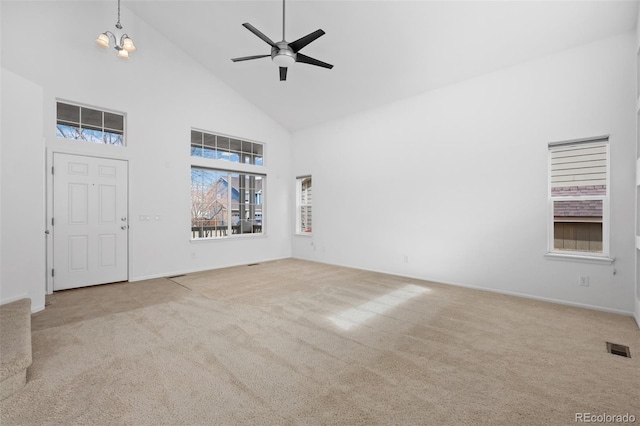 carpeted entrance foyer featuring visible vents, high vaulted ceiling, and ceiling fan with notable chandelier