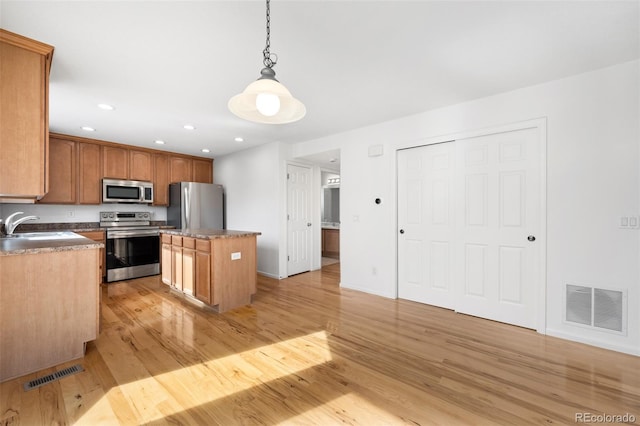 kitchen with a kitchen island, visible vents, appliances with stainless steel finishes, and a sink