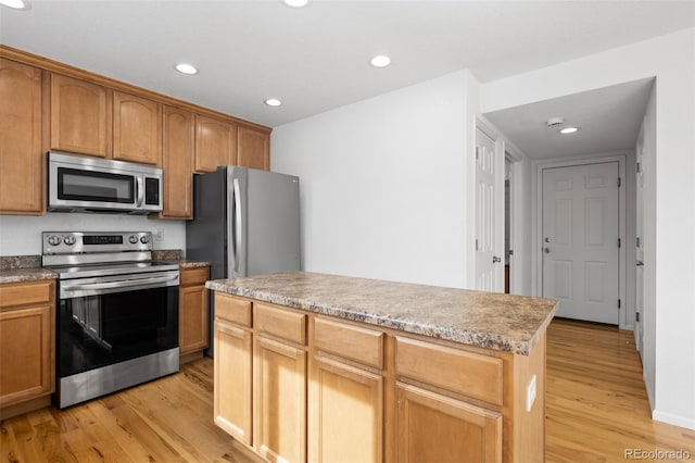 kitchen with recessed lighting, a kitchen island, appliances with stainless steel finishes, and light wood-style flooring