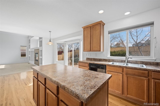 kitchen featuring a sink, black dishwasher, a glass covered fireplace, light wood-type flooring, and a center island