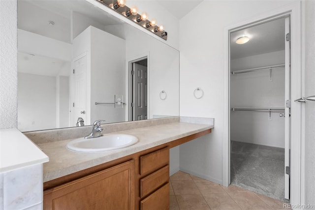 bathroom with tile patterned floors, vanity, and a walk in closet