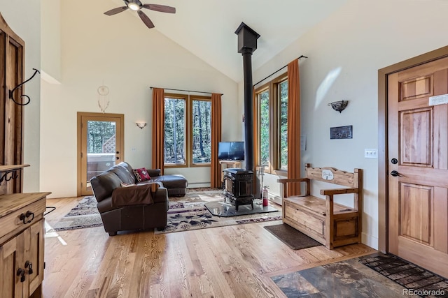 11876 Coal Creek Heights Dr, Golden, CO 80403 - living area featuring a wood stove, plenty of natural light, a ceiling fan, light wood-style flooring, and high vaulted ceiling