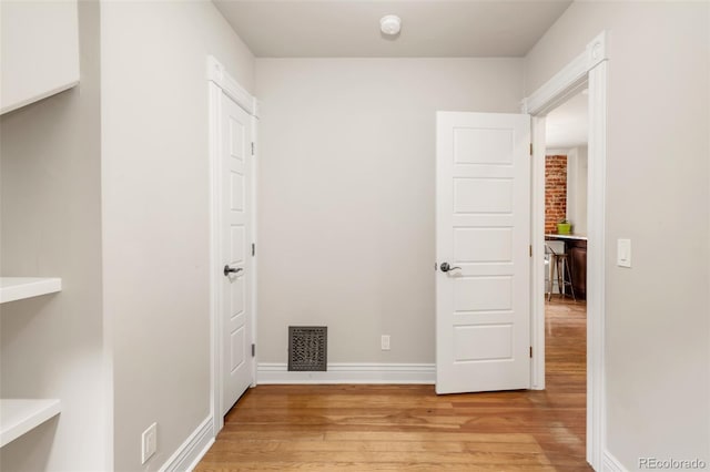 hall with baseboards, light wood-style flooring, and visible vents