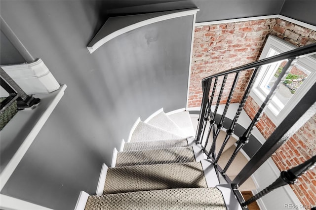 stairway featuring baseboards and brick wall