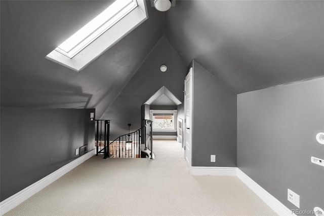 additional living space with carpet flooring, baseboards, and vaulted ceiling with skylight