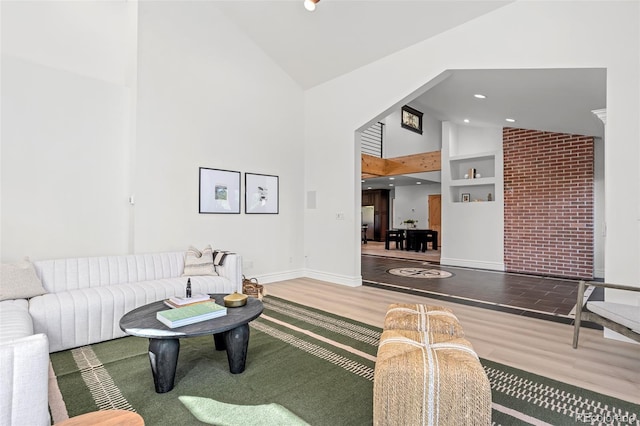 living area with high vaulted ceiling, recessed lighting, wood finished floors, and baseboards