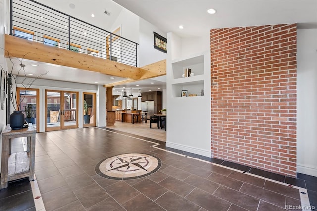 unfurnished living room with baseboards, a towering ceiling, french doors, dark tile patterned floors, and recessed lighting