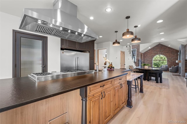 kitchen featuring built in refrigerator, vaulted ceiling, open floor plan, wall chimney range hood, and light wood-type flooring