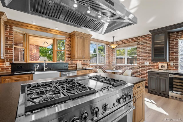 kitchen featuring beverage cooler, brick wall, custom range hood, appliances with stainless steel finishes, and a sink