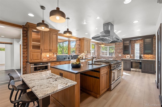 kitchen with island exhaust hood, stainless steel appliances, decorative backsplash, an island with sink, and beverage cooler