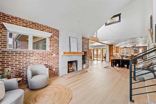 living room with a large fireplace, stairway, brick wall, and wood finished floors