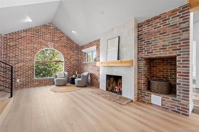 unfurnished living room featuring a fireplace, stairway, brick wall, and wood finished floors