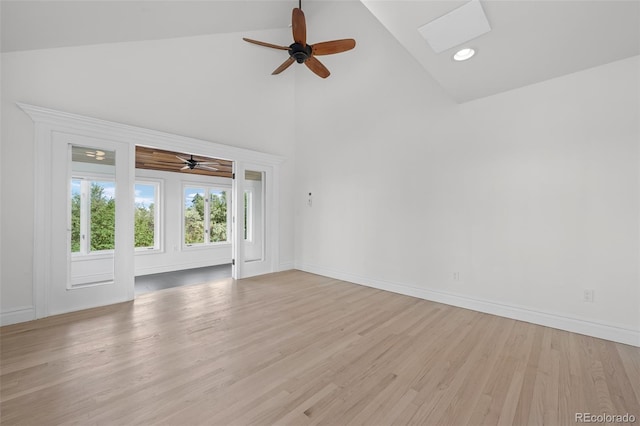 empty room with light wood finished floors, baseboards, and high vaulted ceiling