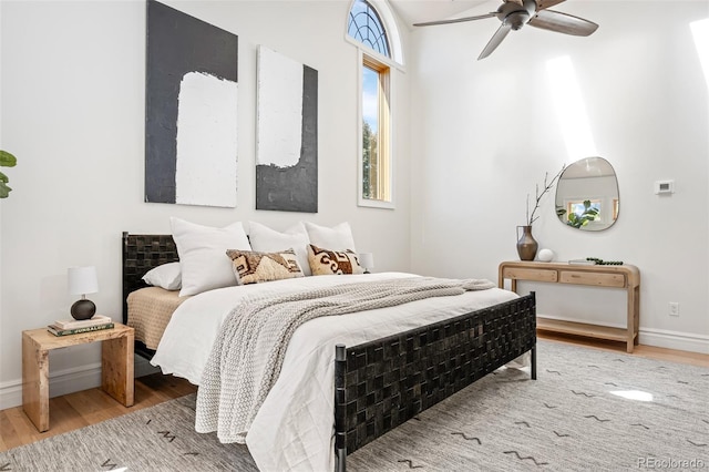 bedroom with a ceiling fan, baseboards, and wood finished floors