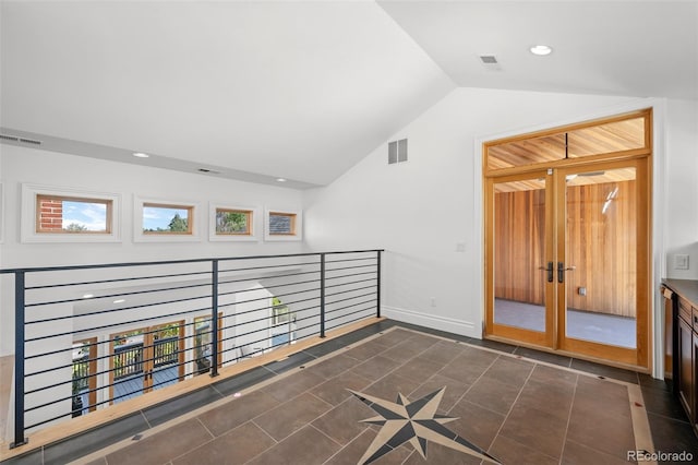 interior space with lofted ceiling, visible vents, baseboards, and dark tile patterned flooring