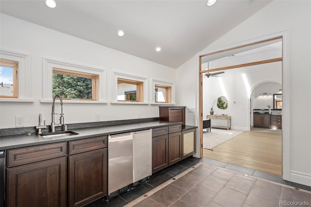 kitchen with arched walkways, recessed lighting, a sink, vaulted ceiling, and dark countertops