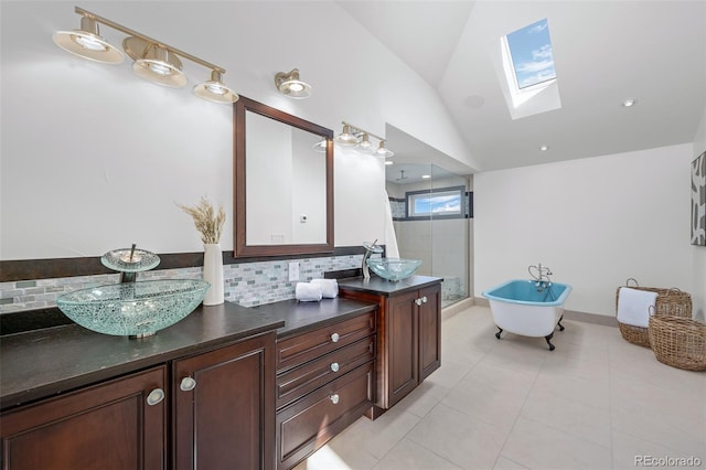 bathroom featuring a freestanding tub, vanity, a stall shower, backsplash, and lofted ceiling with skylight