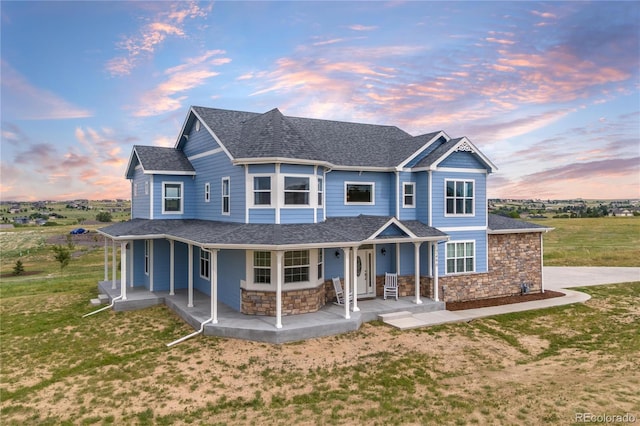 2490 Sagebrush St, Parker, CO 80138 - view of front of house with covered porch, stone siding, a shingled roof, and a lawn