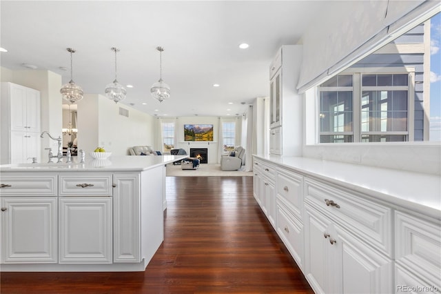 2490 Sagebrush St, Parker, CO 80138 - kitchen with dark wood finished floors, white cabinetry, recessed lighting, a lit fireplace, and light countertops
