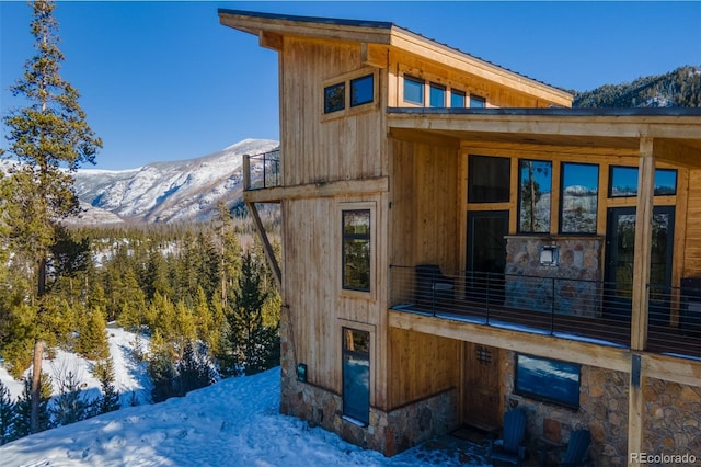 view of snow covered exterior featuring a mountain view and a balcony