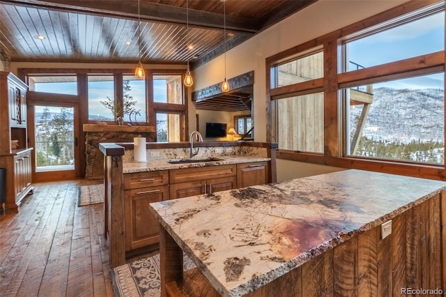 kitchen featuring light stone countertops, sink, hanging light fixtures, wood-type flooring, and wood ceiling