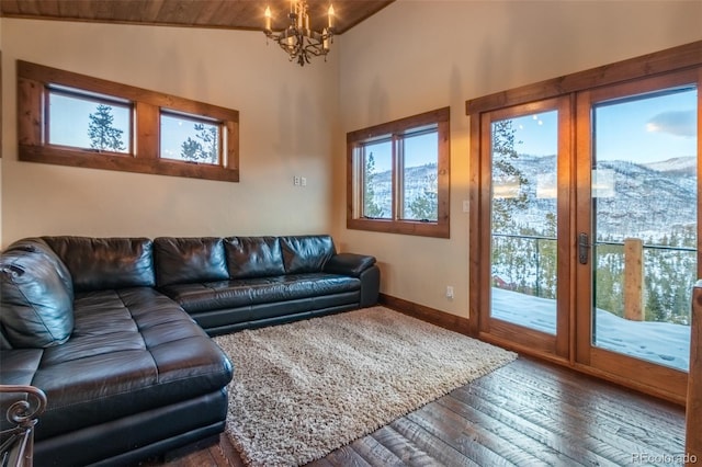 living room with a mountain view, lofted ceiling, dark wood-type flooring, an inviting chandelier, and wood ceiling