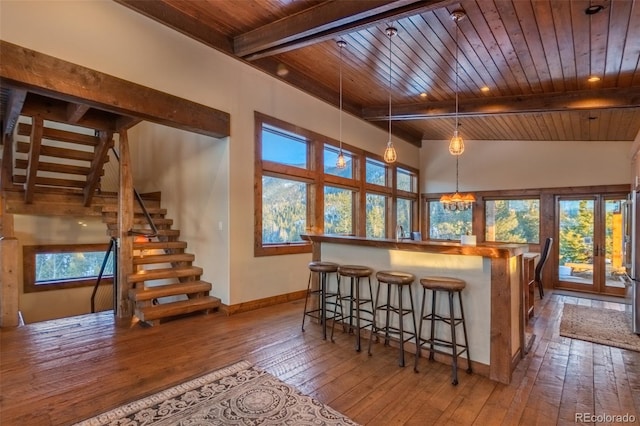 kitchen with beam ceiling, light hardwood / wood-style flooring, a towering ceiling, decorative light fixtures, and wood ceiling