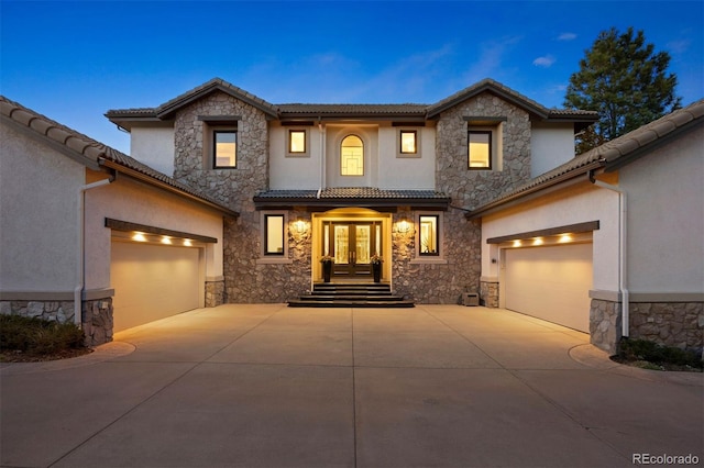 view of front of home featuring concrete driveway, french doors, stone siding, and stucco siding