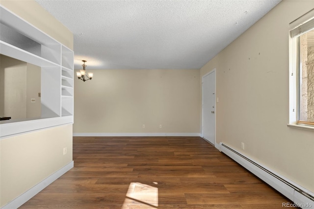 spare room featuring a textured ceiling, dark hardwood / wood-style flooring, a baseboard heating unit, and a notable chandelier