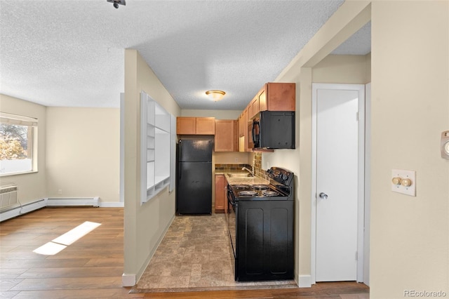 kitchen with light brown cabinetry, light wood-type flooring, a textured ceiling, sink, and black appliances