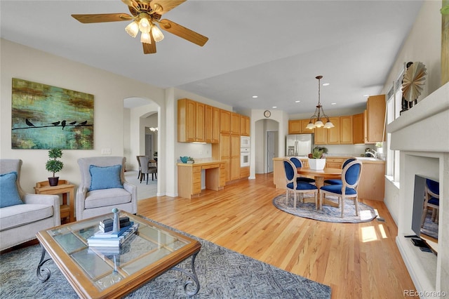 20591 E Weaver Ave, Aurora, CO 80016 - living room featuring arched walkways, light wood-style floors, ceiling fan, and a chandelier