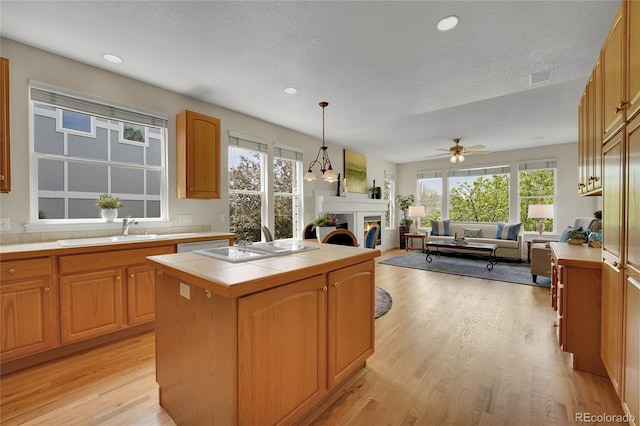 20591 E Weaver Ave, Aurora, CO 80016 - kitchen with a warm lit fireplace, tile countertops, light wood finished floors, open floor plan, and ceiling fan